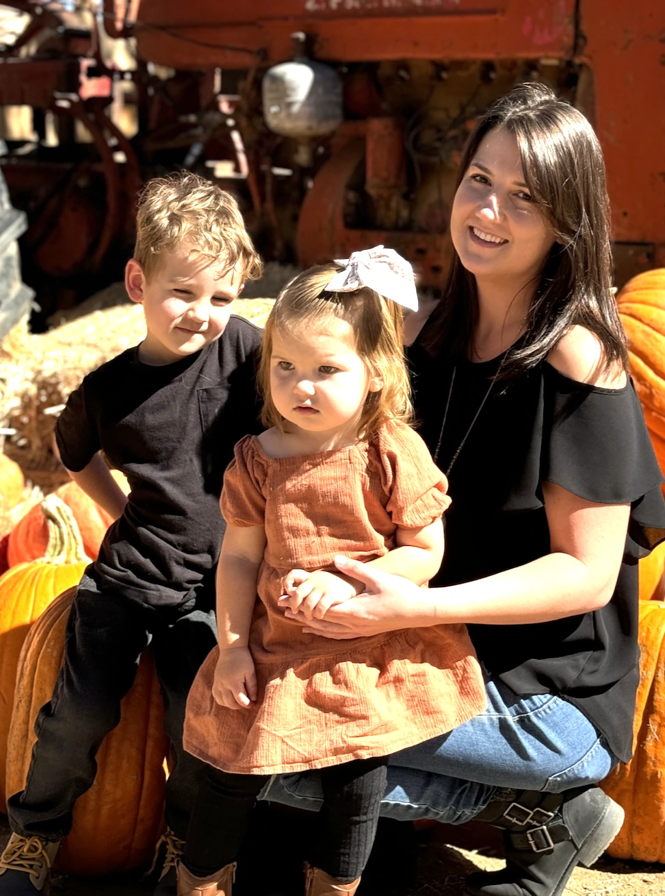 Kylie and her son and daughter sitting on pumpkins for a family picture